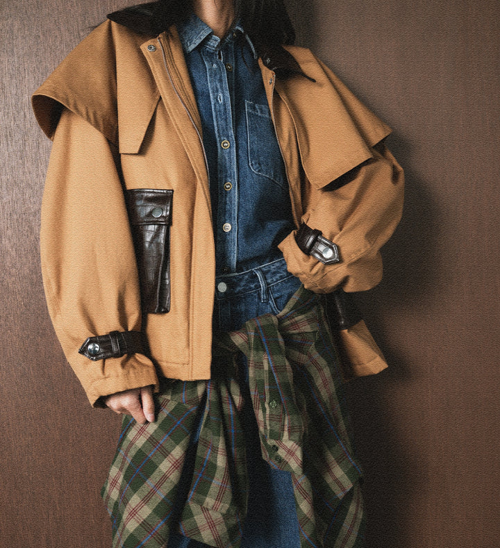 Person wearing a brown coat over a denim shirt with plaid pants against a brown background