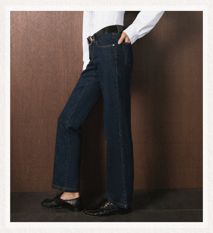 Person wearing dark blue jeans and a white shirt against a brown background