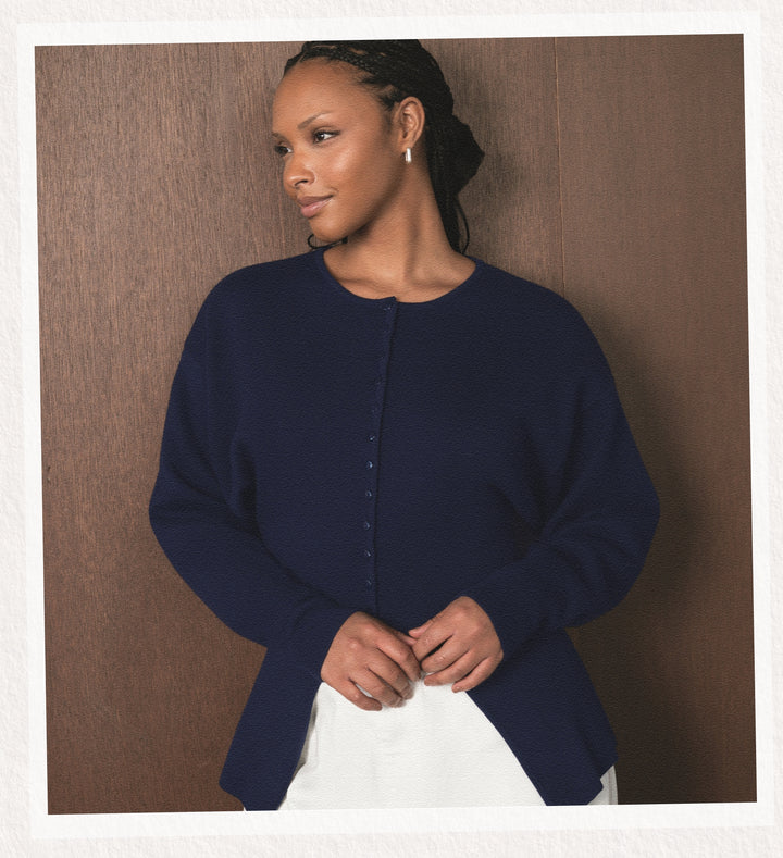 Woman wearing a navy blue cardigan against a brown background